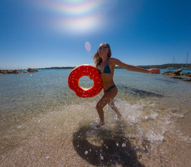 Basking in the Sun: Woman's Delightful Beach Play with Inflatable Ring