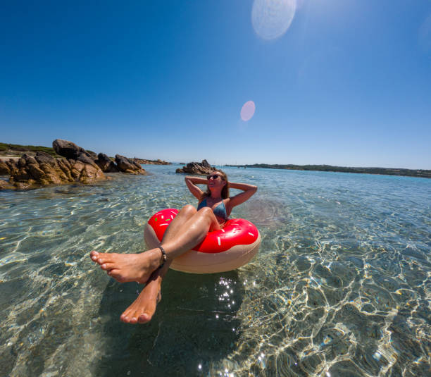 istock Woman Enjoying a Float on Inflatable Ring in Transparent Beach Water 2163176214
