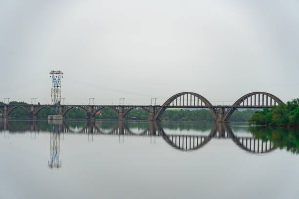 View of river Dnepr and railway ancient arched bridge. Unique construction across wide water 19th century. Railway line along the Merefo-Kherson bridge. Panoramic on modern city and spring landscape.