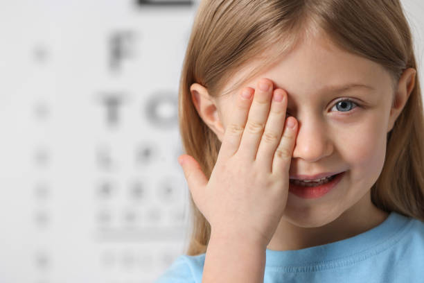 istock Little girl covering her eye against vision test chart 2163176372
