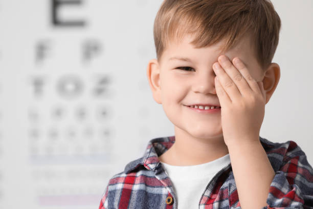 istock Little boy covering her eye against vision test chart 2163176578