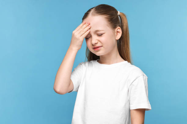 istock Little girl suffering from headache on light blue background 2163176724