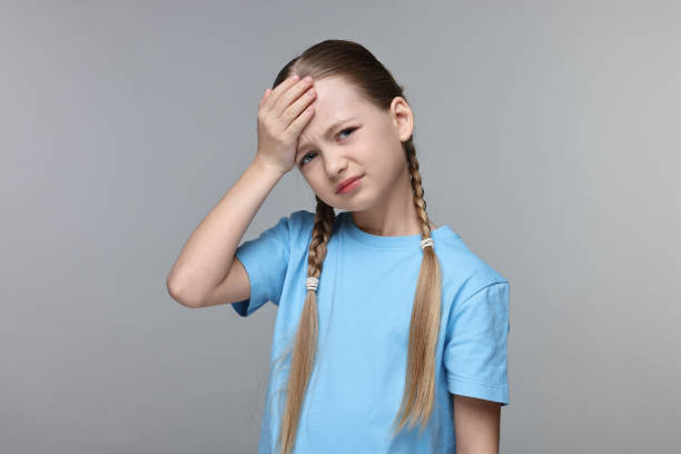 istock Little girl suffering from headache on grey background 2163176745