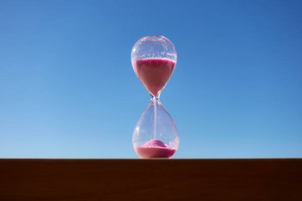 Pink hourglass with blue sky background marking the passage of time