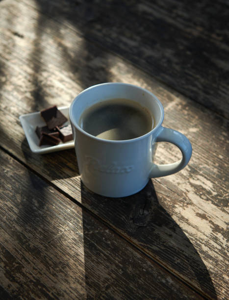 Black Coffee with Chocolate Against Morning Sunlight on a Rusty Wooden Table