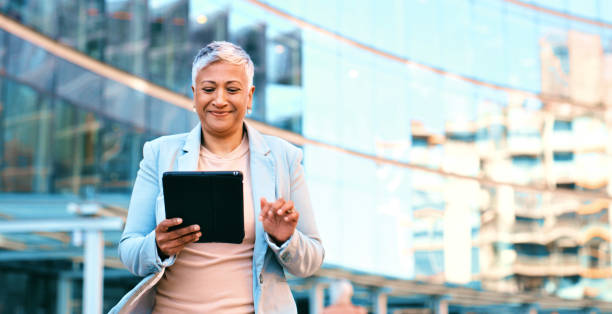 istock Confident Businesswoman Using Tablet Outdoors in Modern Urban Area 2163179609
