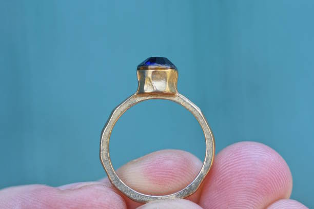 istock fingers holding one yellow gold ring 2163182811