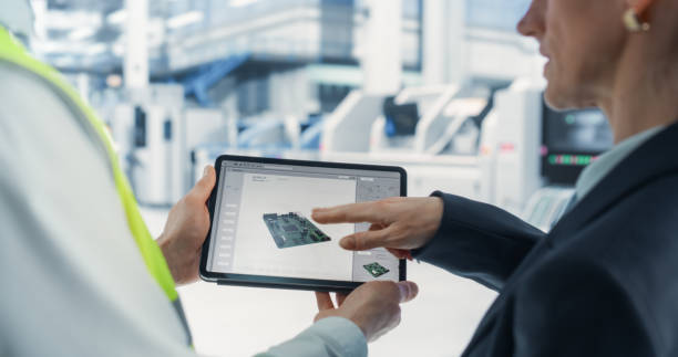 istock Caucasian Female Manager And Male Engineer Using Tablet Computer With Microchip Blueprints at Automated Electronics Factory. Colleagues Discussing Production Of Microprocessors for High-Tech Devices. 2163197440