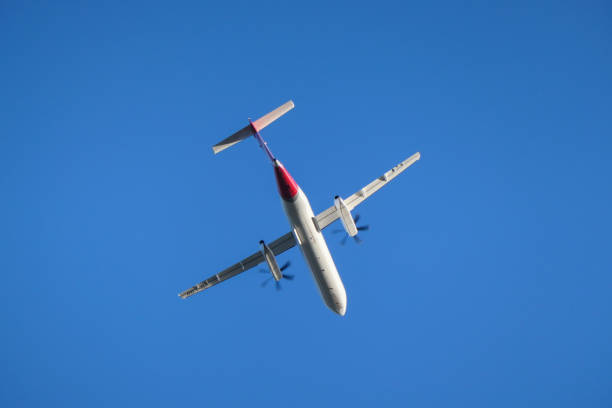 A Qantas De Havilland Canada Dash 8-400 plane, registration VH-LQQ, taking off in strong winds from the east-west runway of Sydney Kingsford-Smith Airport as flight QF2209 to Albury. This image was taken from next to the Cooks River, Banksia on a cold, windy and sunny afternoon on 20 July 2024.