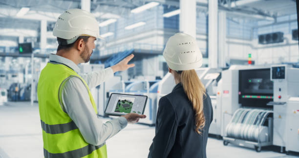 istock Caucasian Female Manager And Male Engineer Using Tablet Computer With Microchip Blueprints at Automated Electronics Factory. Colleagues Discussing Production Of Microprocessors for High Tech Devices. 2163211147
