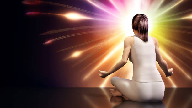 A woman sits in a meditative pose with her back to the viewer, facing a bright light in the distance. The light is emanating a multicolored glow, creating an aura around her.