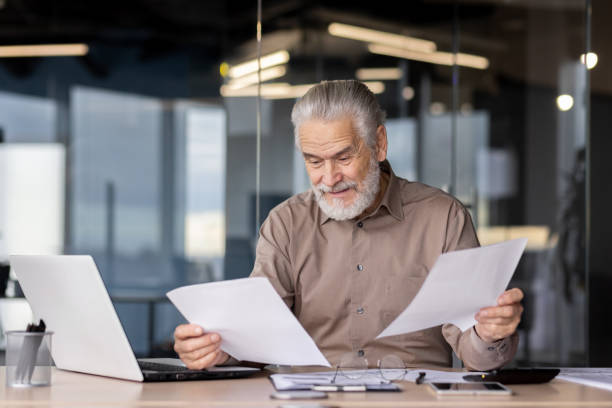 istock Senior businessman reviewing documents at his desk in a modern office setting 2163213374