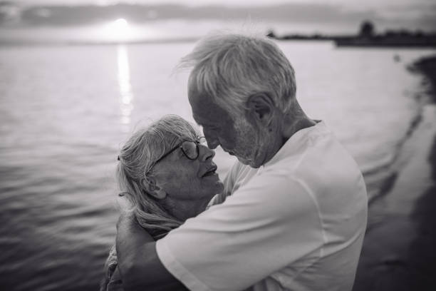 istock Black and white image of elderly couple embracing beach 2163214495