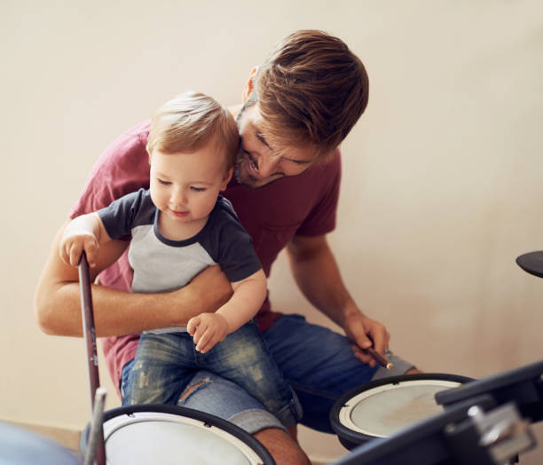 istock Dad, baby and drummer teaching for music development and child learning. Home, father happiness and kid instrument together with youth lesson with a smile, love and parent care at a family house 2163215106