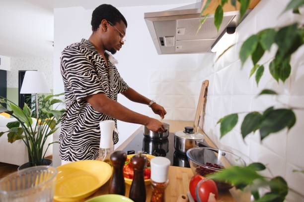 istock Side view of a young man cooking something in the kitchen 2163216137