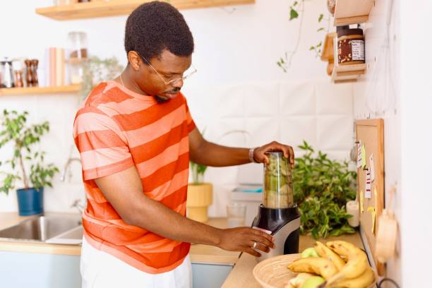 istock Side view of a man using a blender to prepare smoothie 2163216561