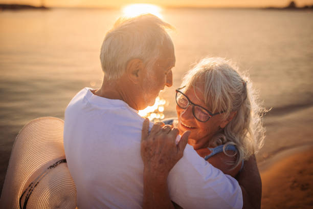 istock Elderly couple embracing on the beach at sunset. 2163216764