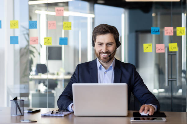 istock Businessman working on laptop with headset in modern office environment 2163217037