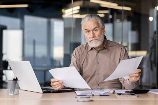 istock Senior businessman reviewing documents in the office with serious expression 2163217618