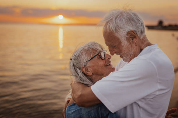 istock Elderly couple hugging on the beach at sunset hour 2163218411