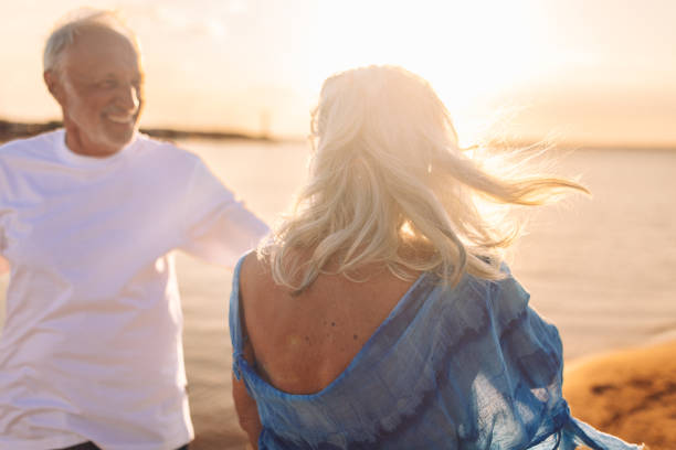 istock Elderly couple walking hand in hand on sandy beach 2163220386