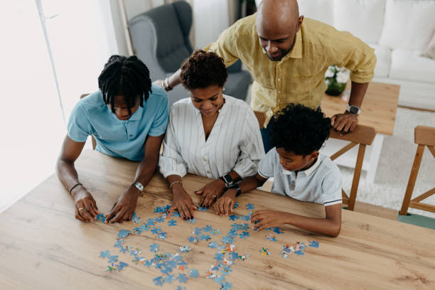 istock Family assembling puzzle together on wooden dining table. 2163221165