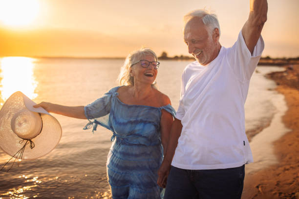 istock Happy elderly couple enjoying walk on sunset beach 2163222902