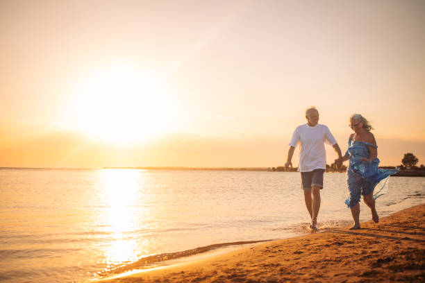 istock Joyful elderly couple running on beach at sunset hour. 2163223728