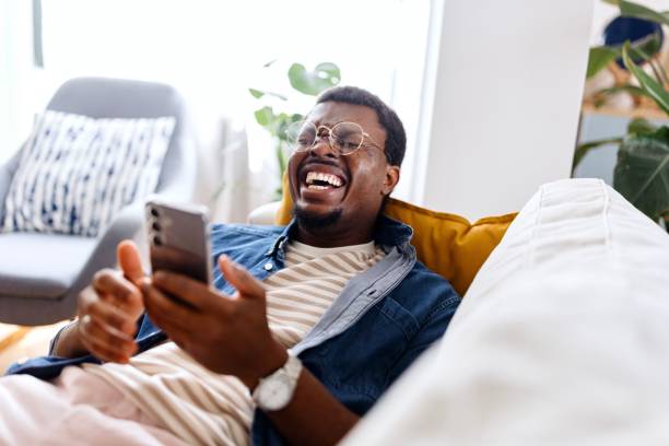 istock Smiling man surfing the net while relaxing on his sofa 2163225414