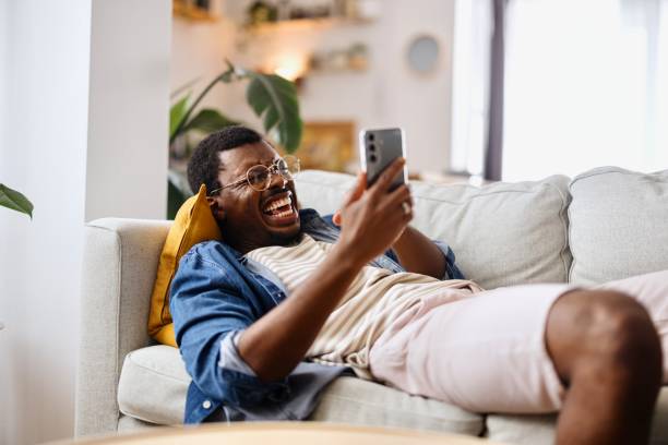 istock Carefree man talking on a video call with someone while lying on the sofa 2163225435