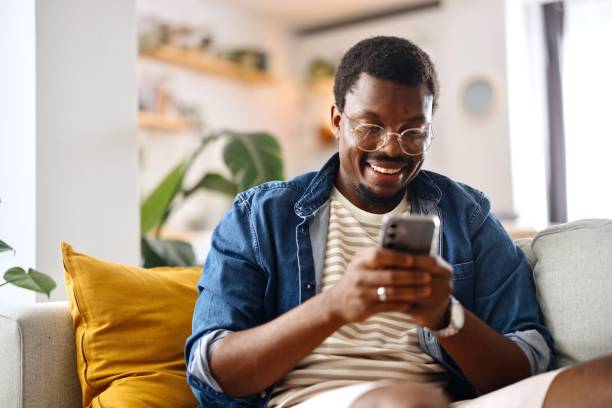istock Close-up of a smiling, black man text messaging with someone 2163225505