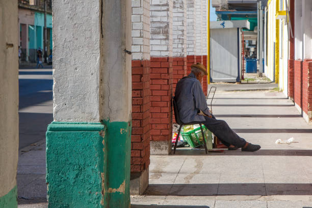 Havana, Cuba - April 20, 2024: A Cuban senior man sits on a building porch.