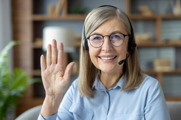 istock Smiling woman with headset waving during virtual meeting in home office setting 2163226652