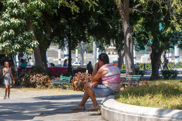 Havana, Cuba - June 2, 2024: A Cuban person sits on a square with little maintenance in the downtown district.