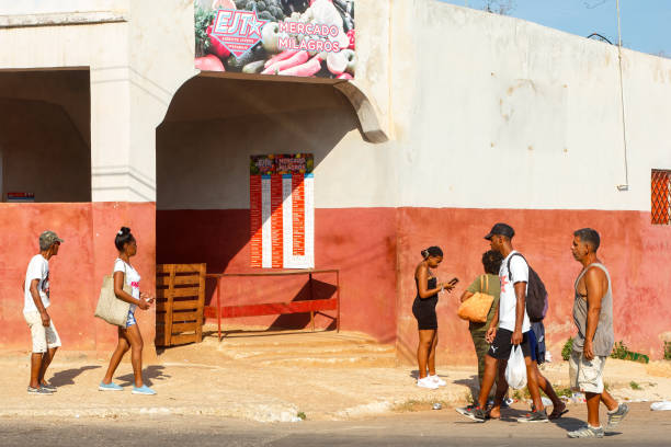 Havana, Cuba - June 2, 2024: Cuban people walk by a market named 'Miracles'. The market is served by the Youth Army of Work (a branch of the Cuban army)