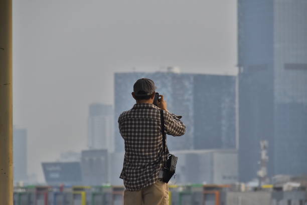 A man stands taking pictures with his cell phone.