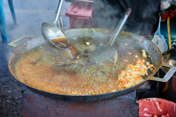 People preparing Pad Thai in cooking pan