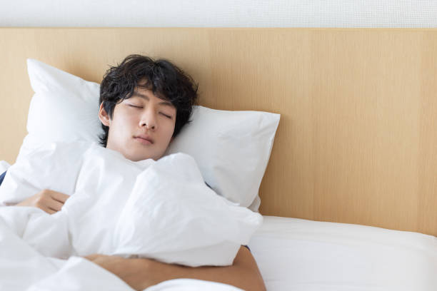 istock A man sleeping comfortably in bed 2163230611