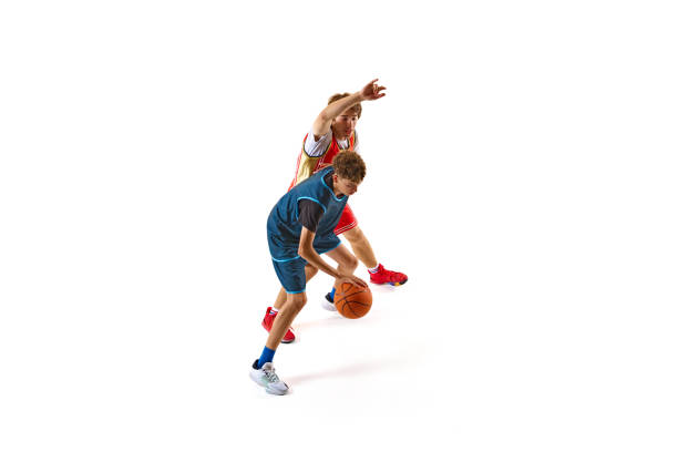 Player in blue jersey demonstrates quick footwork and ball control, evading defender in red who attempting to block his advance against white studio background.
