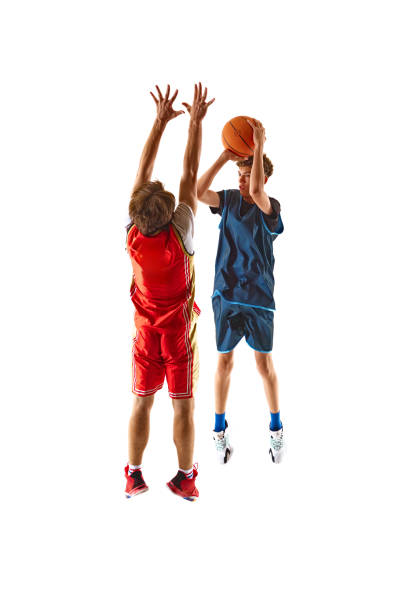 istock Game as player wearing red-jersey attempts shot under heavy pressure from opponent blue-jersey defender against white studio background. 2163238635
