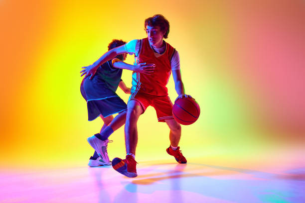 istock Intense basketball practice with two athletes in neon light against gradient studio background. Their movements reflect commitment and athleticism. 2163238641