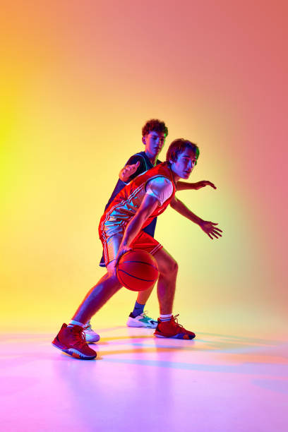 istock Two basketball players practice with intensity, showcasing their skill and commitment to game in neon light against gradient studio background. 2163238643