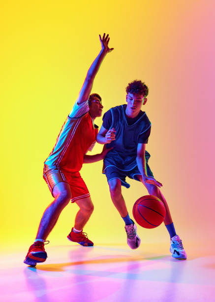 istock Basketball training with two dedicated athletes in neon light against gradient studio background, emphasizing their agility and determination. 2163238646