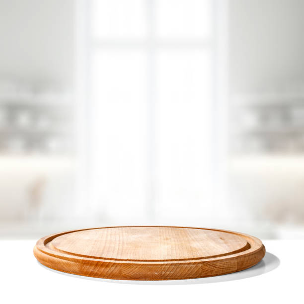 istock Wooden cutting board on white table with copy space for products and blurred kitchen interior. 2163240978