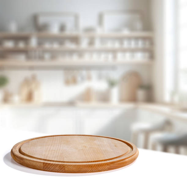 istock Wooden cutting board on white table with copy space for products and blurred kitchen interior. 2163242523