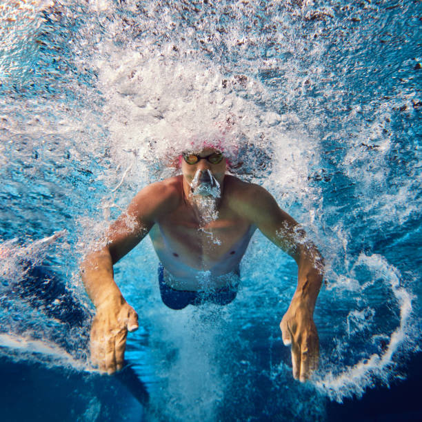 istock Focused swimmer, seen underwater during training, wears pink cap and goggles, his powerful strokes creating dynamic water movement. 2163243992