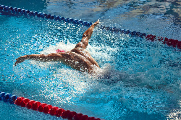 Competitive swimmer is captured mid-butterfly stroke, arms wide and water splashing around as they glide through the pool