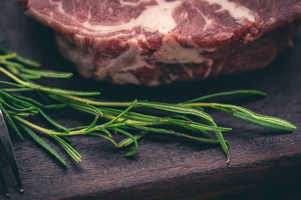 Steak marinating on wooden tray rosemary macrophotography