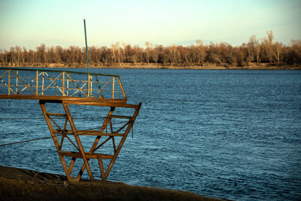 Amidst autumn trees, a riverbank displays a grand metal structure, showing a tranquil scenery by the river