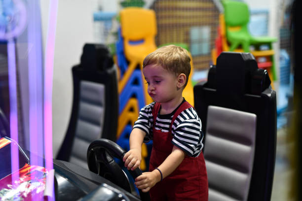 Smiling Toddler Learning How To Work The Steering Wheel On Arcade Racing Game